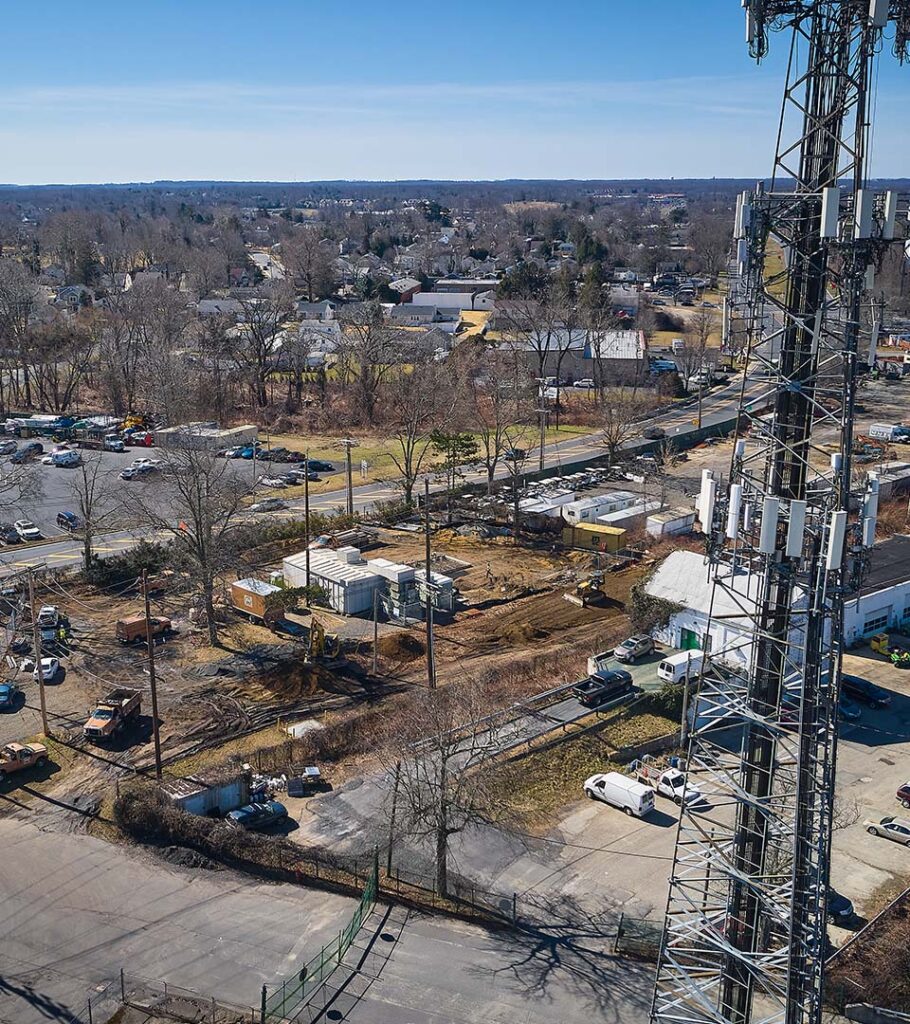 Aerial view of a telecommunications site featuring a tall cell tower with multiple antennas.